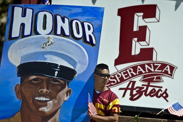 Student holding flags beside "Honor" mural