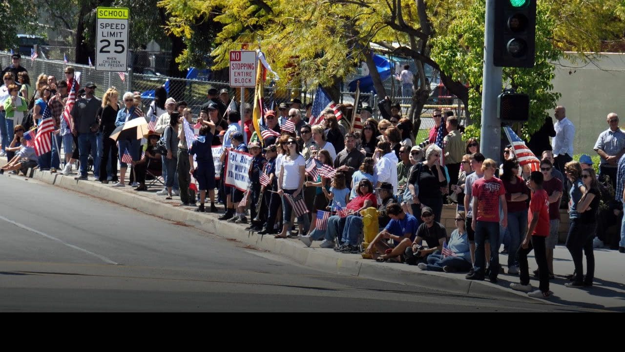 Crowd on sidewalk waving American flags